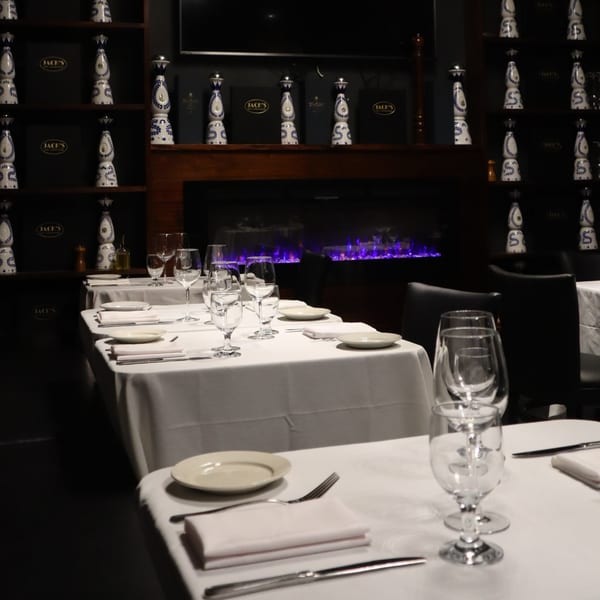 Elegant dining room at Jack's Bar And Steakhouse with set tables, a fireplace, and decorative bottles.