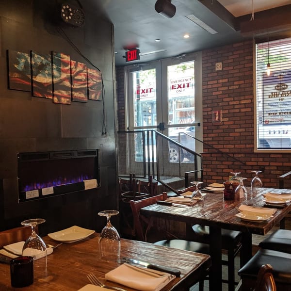 Interior of Jack's Bar And Steakhouse with set tables, a fireplace, and an American flag art piece.