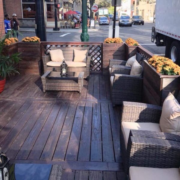 Outdoor patio at Jack's Bar And Steakhouse with wicker seating, planters, and a street view.