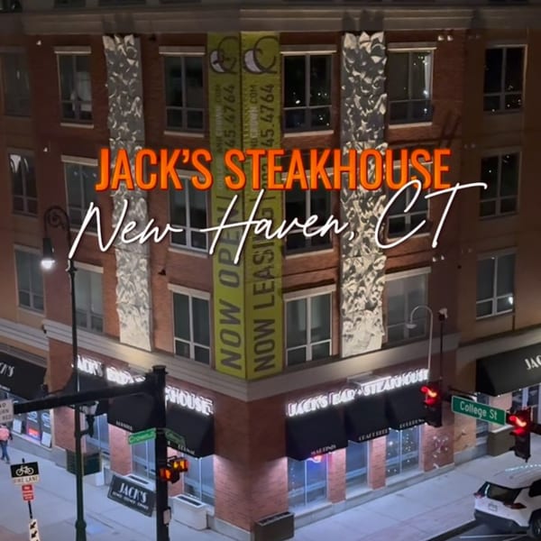 Exterior of Jack's Bar And Steakhouse at night, with illuminated signs and streetlights.